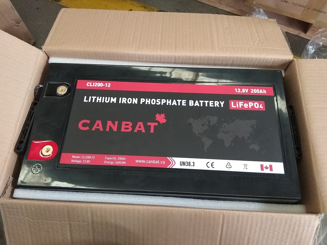 Eine 12-Volt-Lithium-Eisenphosphat-Batterie (LiFePO4) mit 200 Ah in einem Karton, Draufsicht auf die beschriftete Oberseite mit Polen.